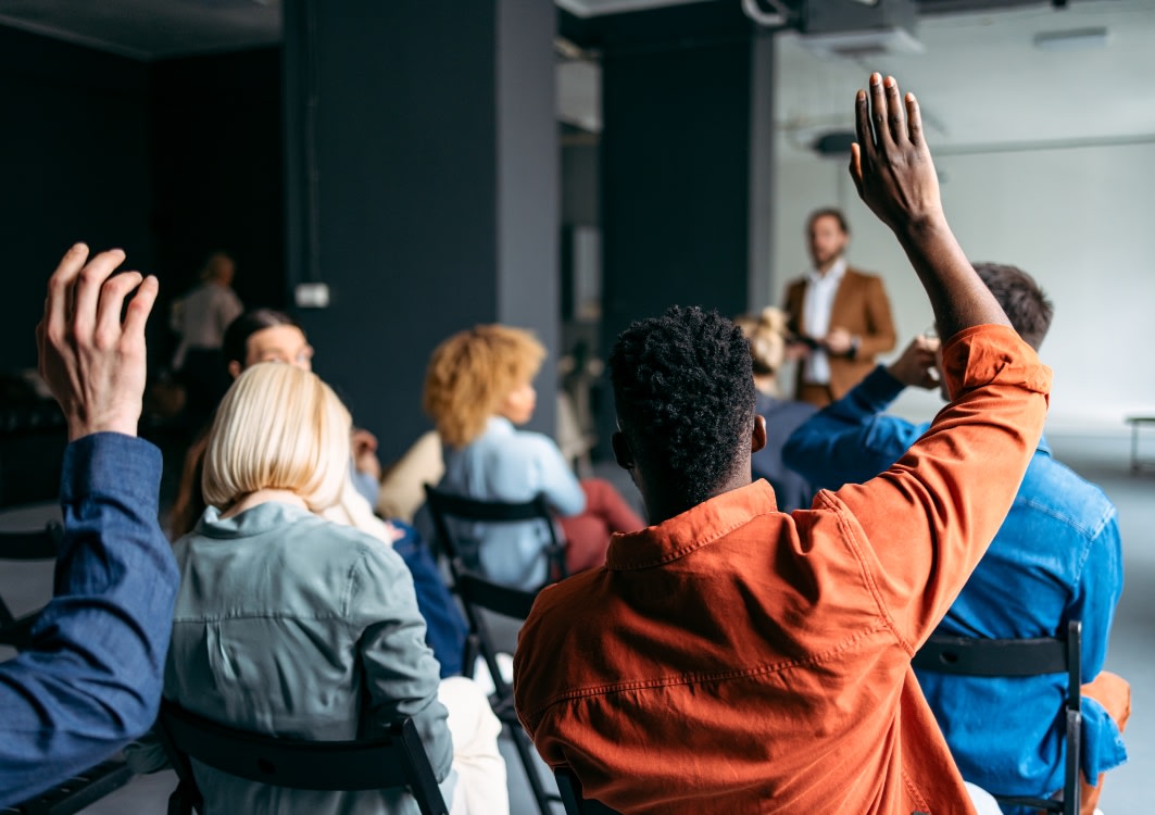 Classroom of adults with their hands up